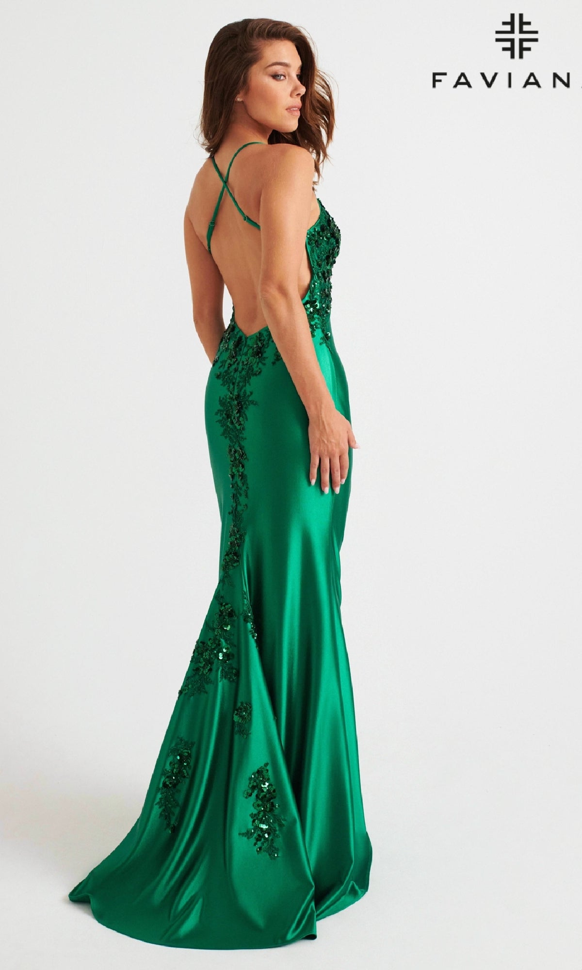 A woman wears the Faviana 11247, a floor-length green prom dress with sequins, an open back, and stretch satin fabric, posing before a white background with the Faviana logo.